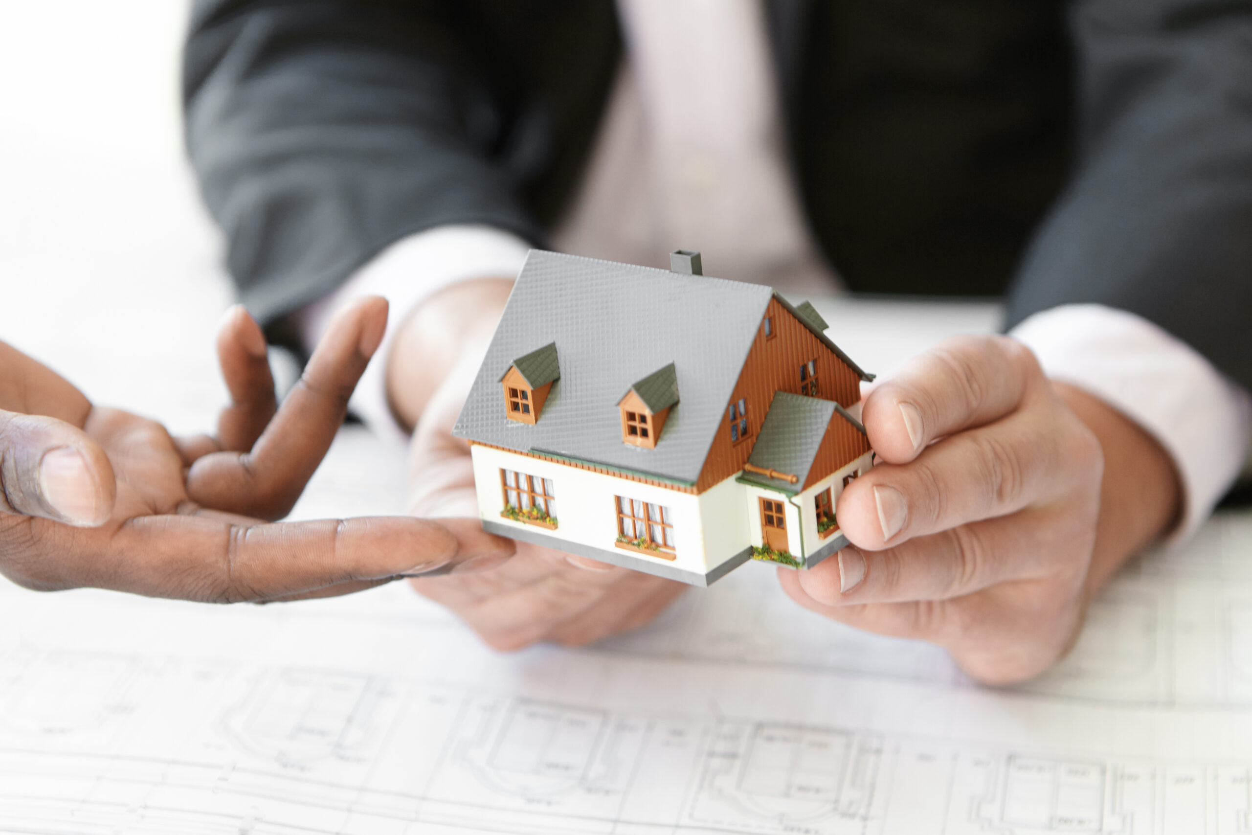 Architecture, building and construction concept. Cropped shot of two engineers evaluating design of new housing project. African architect making presentation of scale model house to his partner